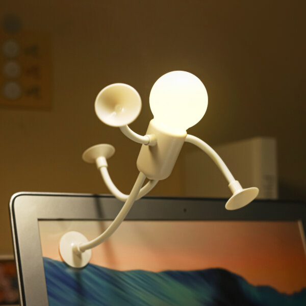 Creative humanoid suction cup night light mounted on a computer screen, used as a reading or ambient lamp