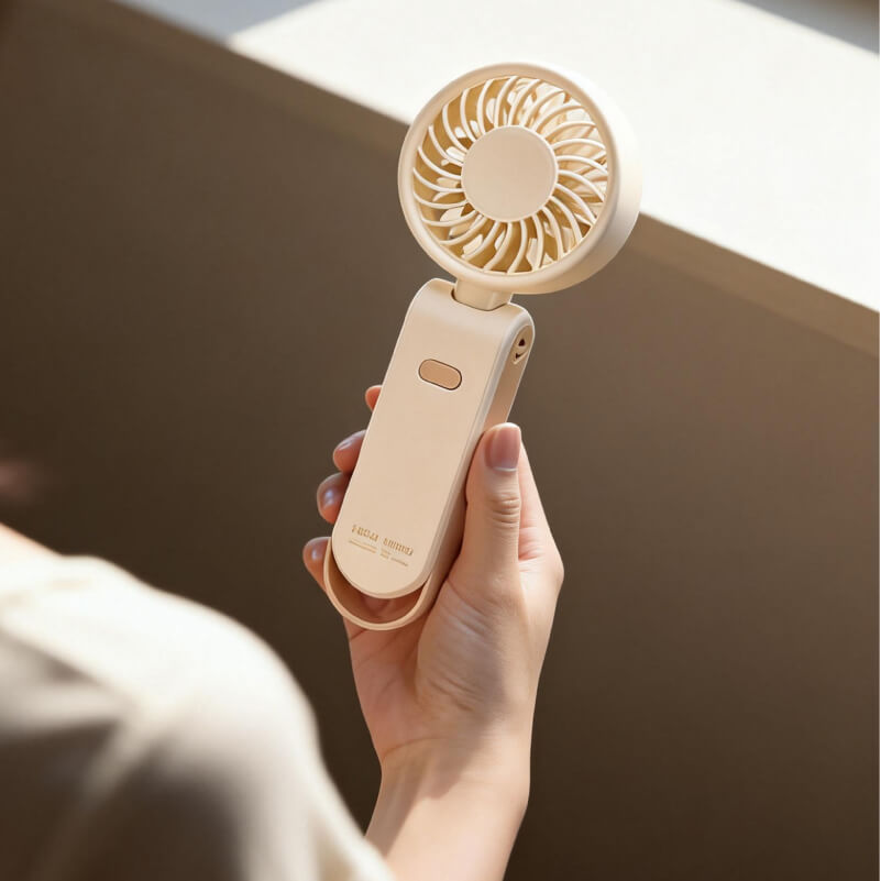 Foldable Neck and Bag Hanging High-Speed Handheld Fan, showing its beige body, folding joint, front grille, and multifunctional hanging loop structure at the bottom.