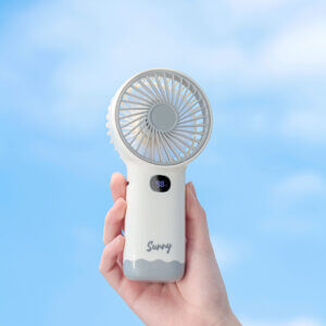 Smart Digital Display Portable Rechargeable Handheld Desktop Fan, showing its white body, warm beige front grille, LED digital display screen, side charging port, and wavy base stand.