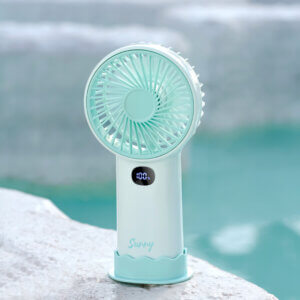 Smart Digital Display Portable Rechargeable Handheld Desktop Fan, showing its white body, warm beige front grille, LED digital display screen, side charging port, and wavy base stand.