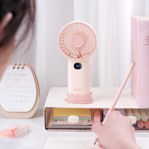 Smart Digital Display Portable Rechargeable Handheld Desktop Fan, showing its white body, warm beige front grille, LED digital display screen, side charging port, and wavy base stand.